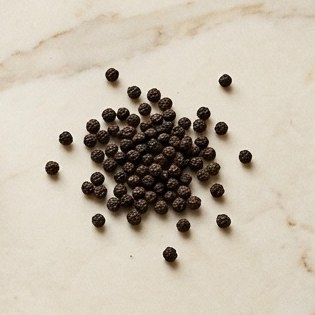 Black peppercorns scattered on marble